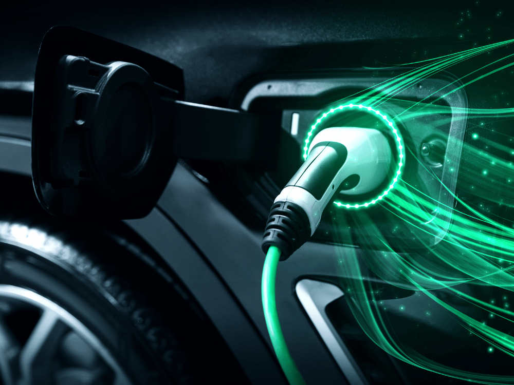 Close-up of an electric vehicle being charged, showing the connected charging cable with glowing green energy lines emanating from it. This image highlights the advanced sustainable vehicle materials integrated into EV packaging.