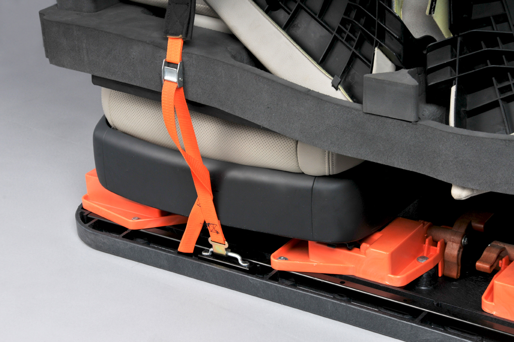 Close-up of an automotive pallet base with secured orange straps.