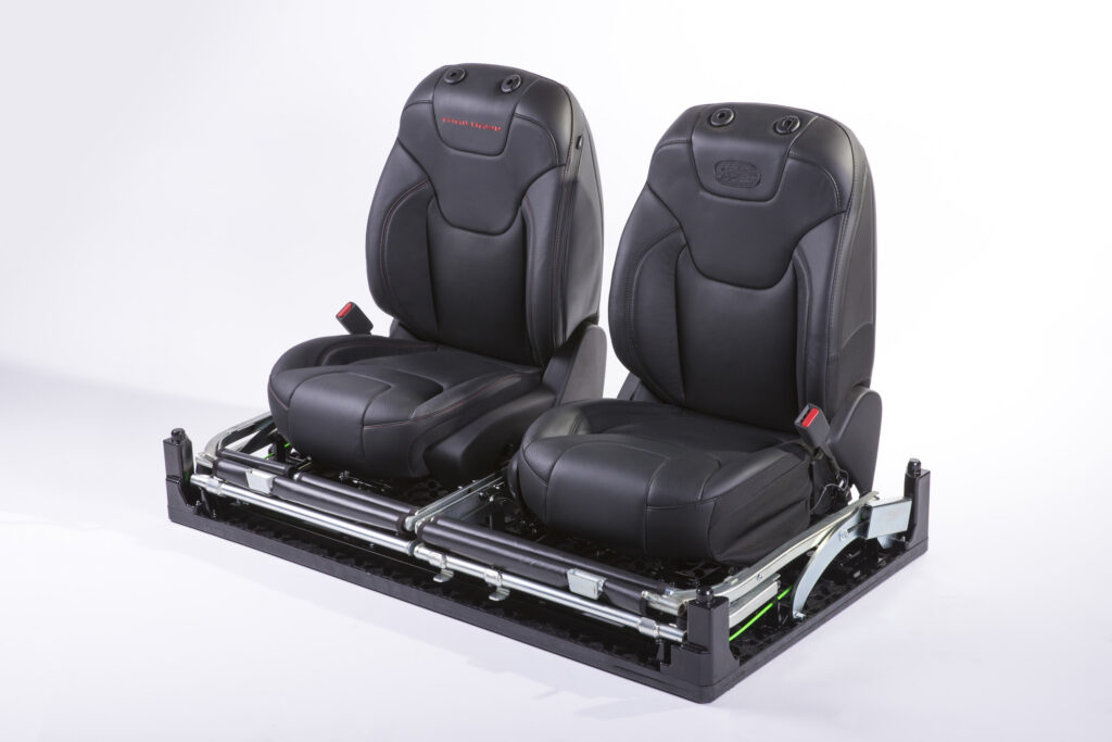 Two black automotive seats are securely positioned on plastic pallet.